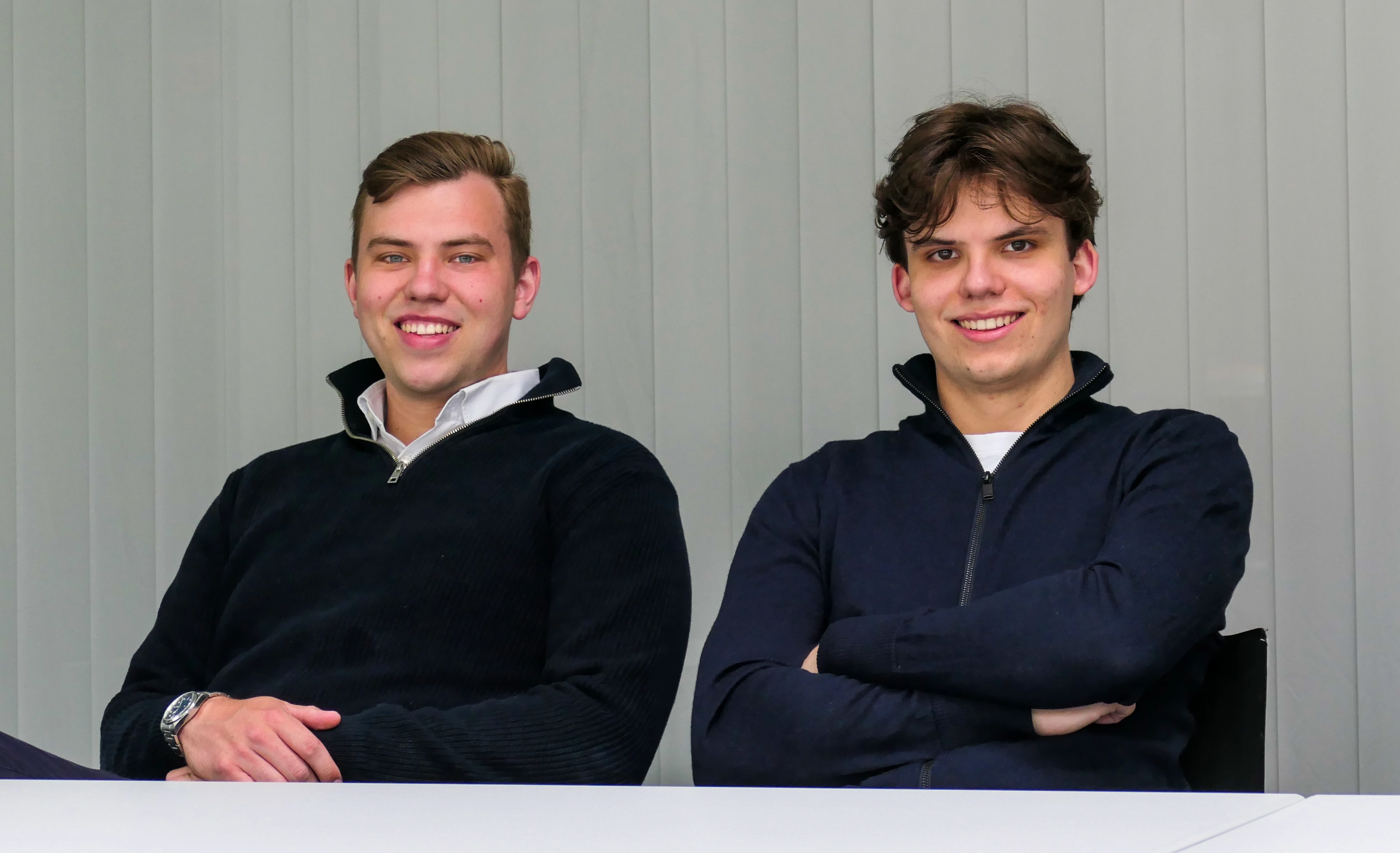 Luis und Tim Höltkemeyer, die Gründer von H&H Creative, sitzen lächelnd am Tisch